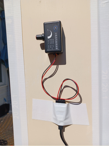 A cable plug is taped to the side of a wooden frame, leaving slack in the wires going up to a knob assembly.